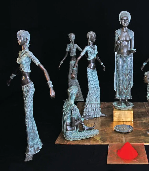 A group of figurative sculptures displayed against a dark background