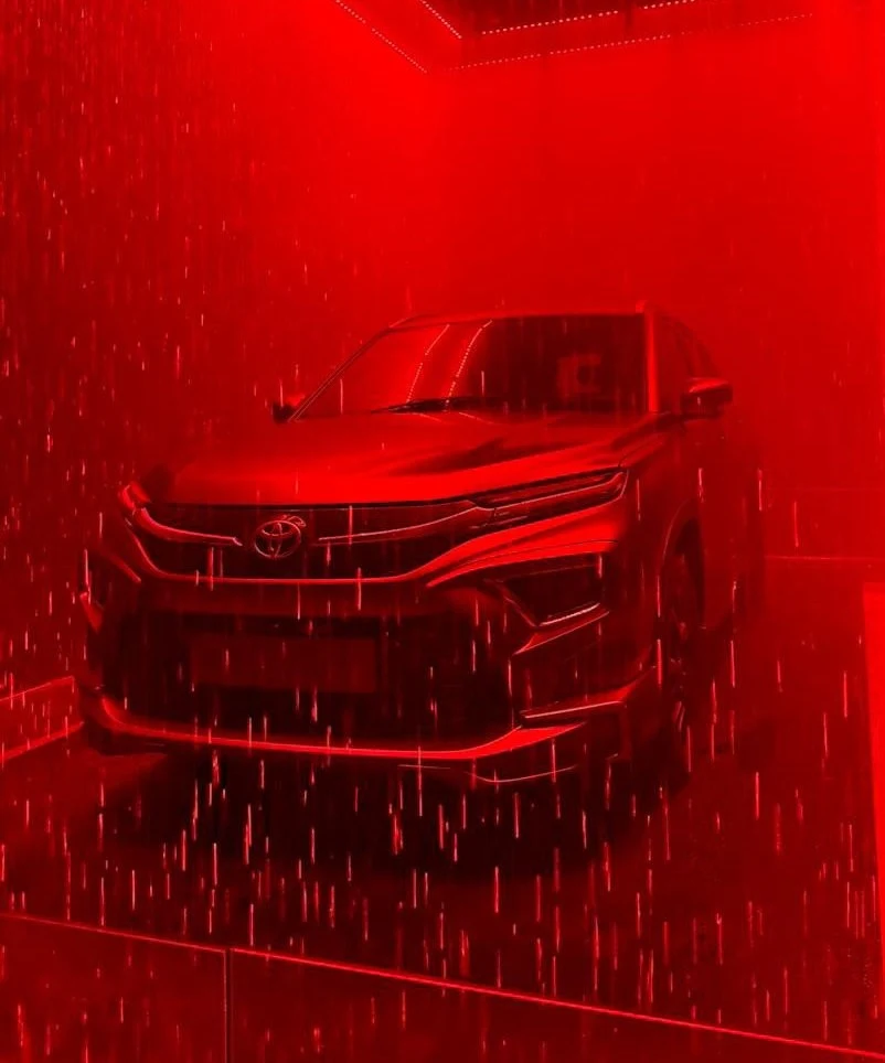 A red-lit installation featuring a suspended Toyota car